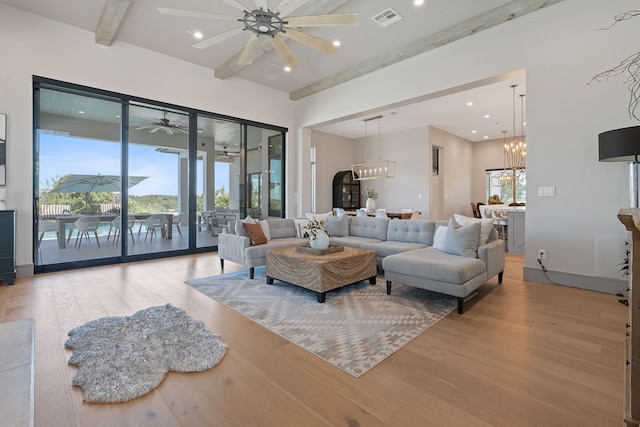 living room with ceiling fan with notable chandelier and light hardwood / wood-style flooring