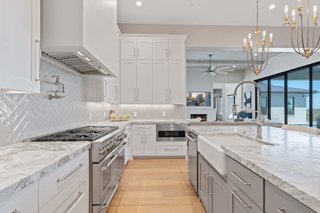 kitchen featuring premium range hood, white cabinets, appliances with stainless steel finishes, and decorative backsplash