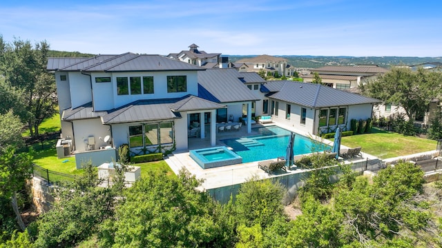 rear view of property with central AC unit, a patio area, outdoor lounge area, a pool with hot tub, and a lawn