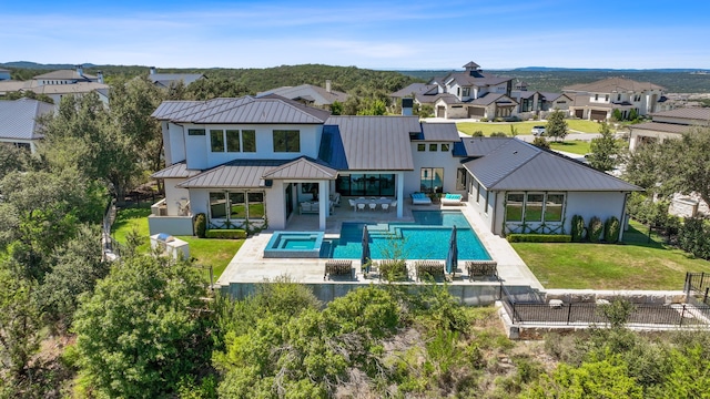 rear view of property with a patio area and a pool with hot tub