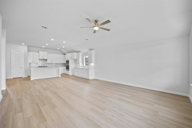 unfurnished living room featuring vaulted ceiling, light hardwood / wood-style flooring, ceiling fan, and sink