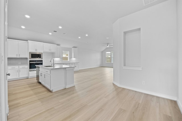 kitchen featuring sink, appliances with stainless steel finishes, a center island with sink, white cabinets, and light wood-type flooring