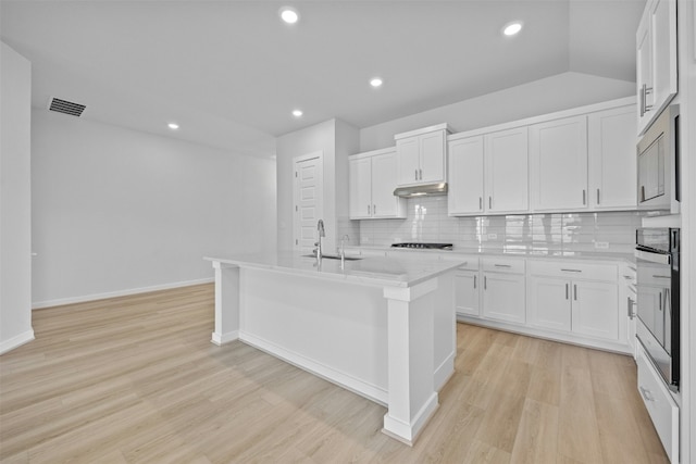 kitchen featuring light hardwood / wood-style flooring, stainless steel appliances, white cabinetry, and an island with sink