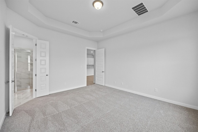 unfurnished bedroom featuring carpet flooring and a tray ceiling