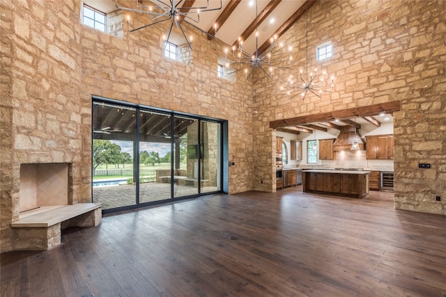 unfurnished living room with a healthy amount of sunlight, high vaulted ceiling, and a chandelier