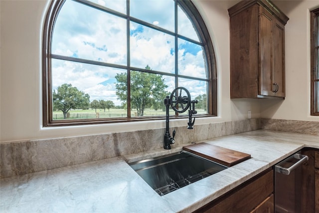 kitchen with stainless steel dishwasher, light stone countertops, plenty of natural light, and sink