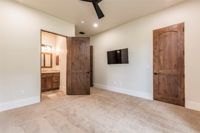 unfurnished bedroom featuring ceiling fan, light colored carpet, and ensuite bath