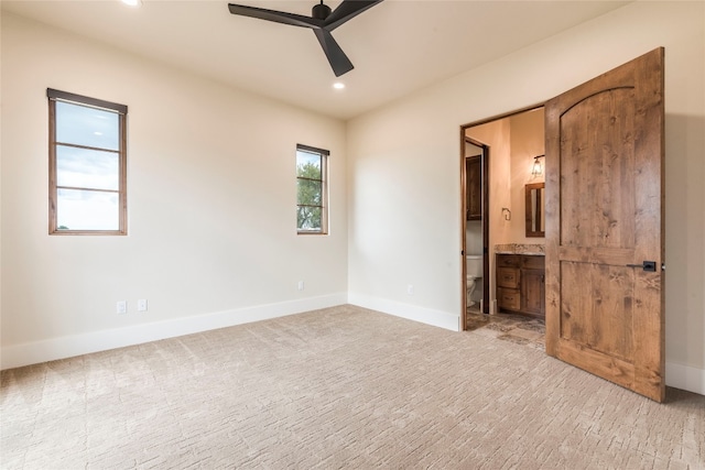 unfurnished bedroom with ceiling fan, light carpet, and ensuite bathroom