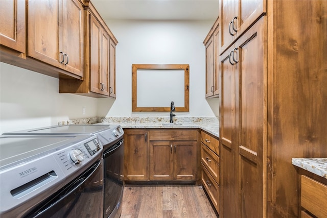 washroom featuring cabinets, washer and clothes dryer, sink, and light hardwood / wood-style floors