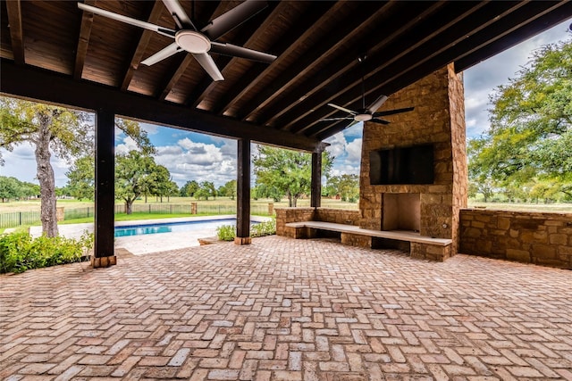 view of patio featuring a fenced in pool, an outdoor stone fireplace, and ceiling fan