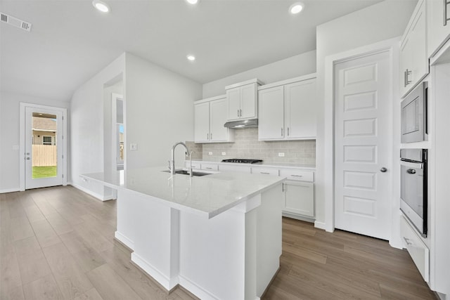 kitchen with a center island with sink, white cabinetry, and light hardwood / wood-style flooring