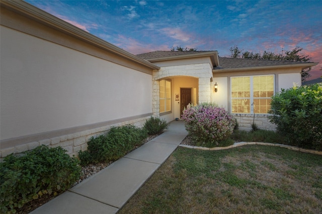 exterior entry at dusk featuring a yard