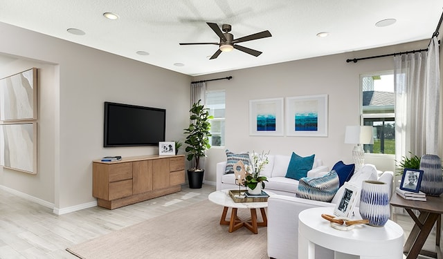 living room with a textured ceiling, light hardwood / wood-style floors, and ceiling fan