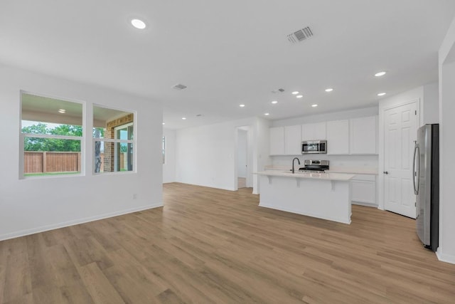 1004 Stonehill Dr, Georgetown, TX 78633 - kitchen featuring appliances with stainless steel finishes, a sink, open floor plan, light wood-style flooring, and light countertops