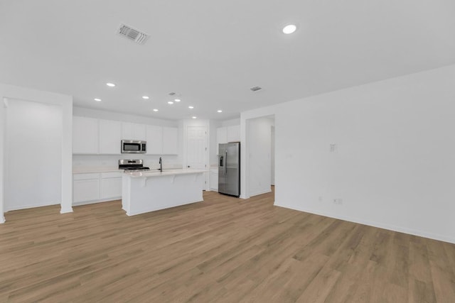1004 Stonehill Dr, Georgetown, TX 78633 - kitchen featuring appliances with stainless steel finishes, open floor plan, recessed lighting, a breakfast bar, and white cabinets