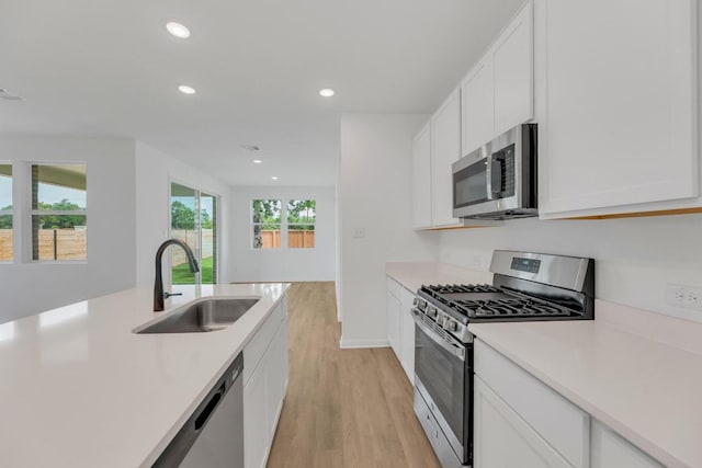 1004 Stonehill Dr, Georgetown, TX 78633 - kitchen featuring stainless steel appliances, a sink, light wood-type flooring, recessed lighting, and white cabinetry