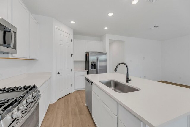 1004 Stonehill Dr, Georgetown, TX 78633 - kitchen with appliances with stainless steel finishes, a sink, light wood finished floors, white cabinetry, and light countertops