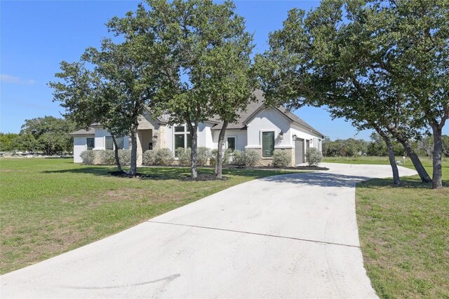 view of front of property with stucco siding, stone siding, driveway, and a front lawn