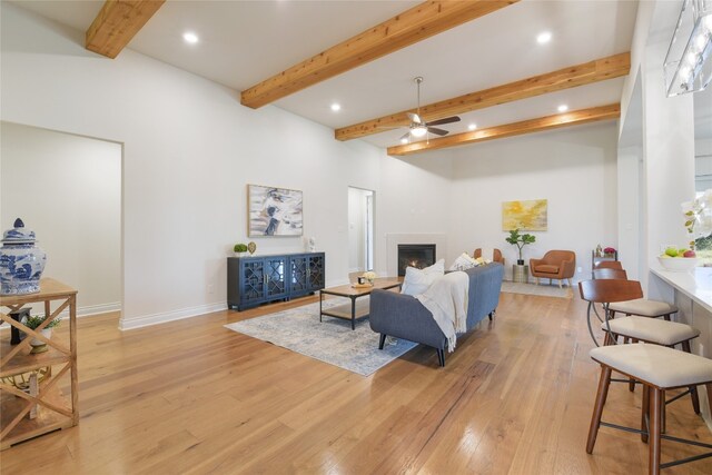 living room featuring ceiling fan, light hardwood / wood-style flooring, and beam ceiling