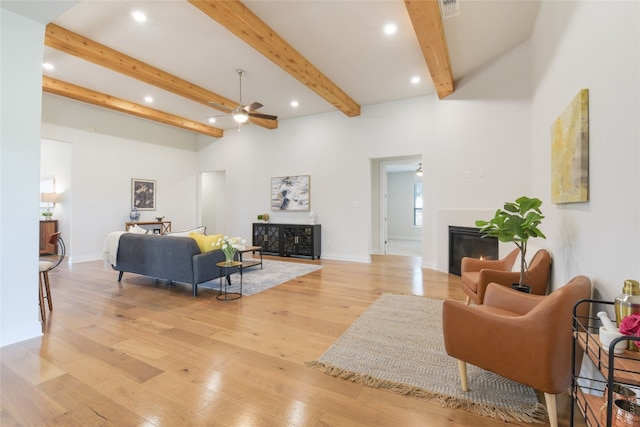 living room featuring ceiling fan, light wood-type flooring, and beam ceiling