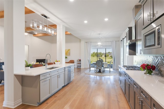 kitchen with sink, decorative light fixtures, light hardwood / wood-style flooring, appliances with stainless steel finishes, and an inviting chandelier