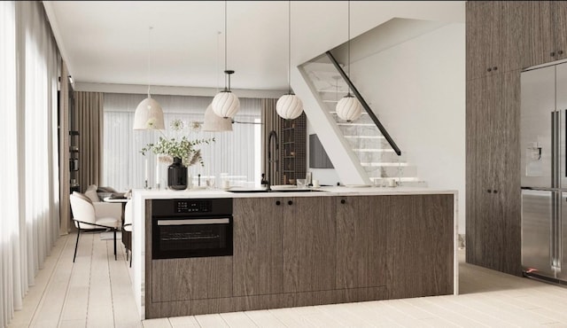 kitchen featuring light wood-type flooring, pendant lighting, built in refrigerator, oven, and sink