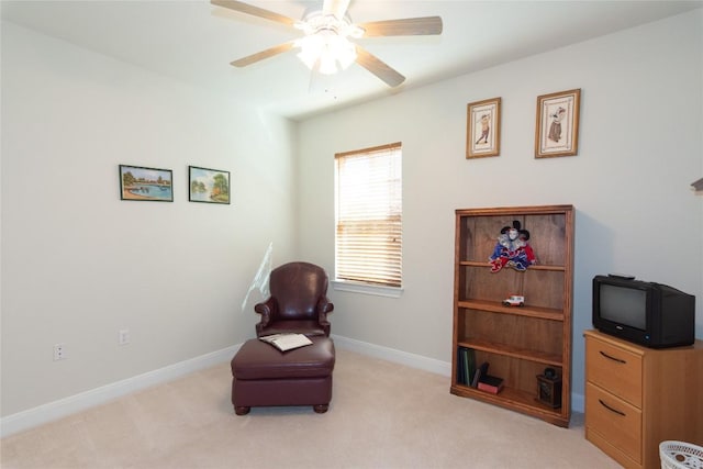 living area with baseboards, ceiling fan, and light colored carpet