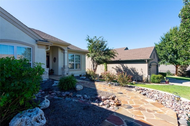 ranch-style house with a shingled roof, a patio area, and stucco siding