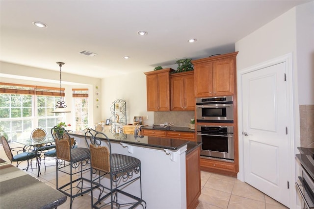 411 Palmetto Dr, Georgetown, TX 78633 - kitchen featuring light tile patterned floors, a breakfast bar area, brown cabinets, recessed lighting, and pendant lighting