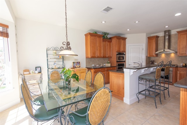 kitchen with tasteful backsplash, a kitchen island, pendant lighting, and wall chimney range hood