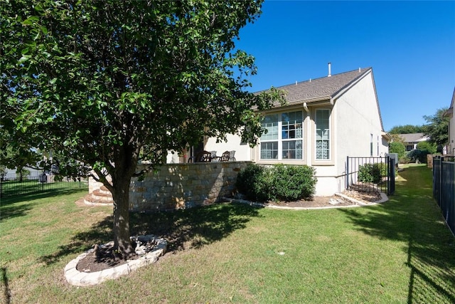 view of side of home featuring fence, a lawn, and stucco siding