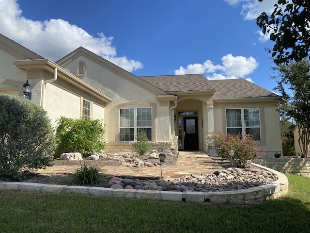 view of front of property with roof with shingles and stucco siding