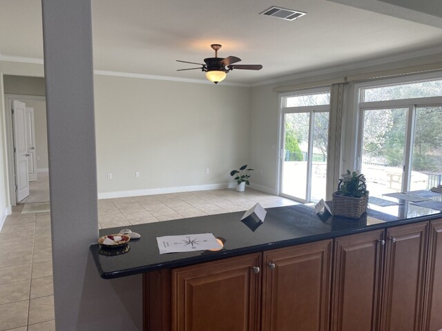 411 Palmetto Dr, Georgetown, TX 78633 - kitchen with dark countertops, light tile patterned floors, crown molding, ceiling fan, and baseboards
