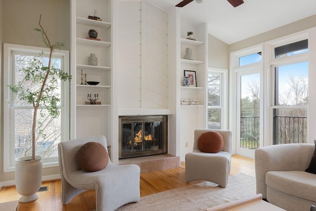 living area featuring built in shelves, light wood-type flooring, and a fireplace