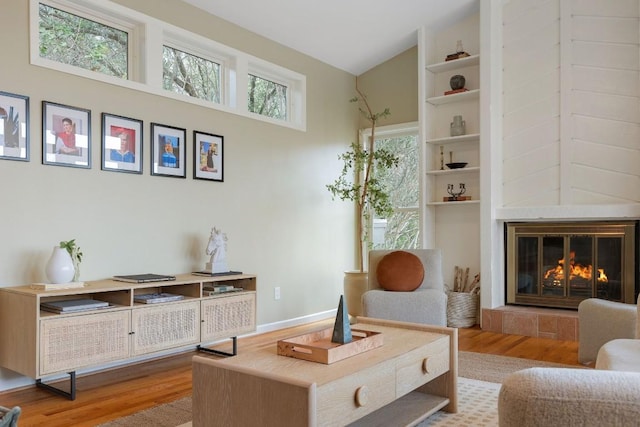 sitting room featuring lofted ceiling, a tiled fireplace, and wood finished floors