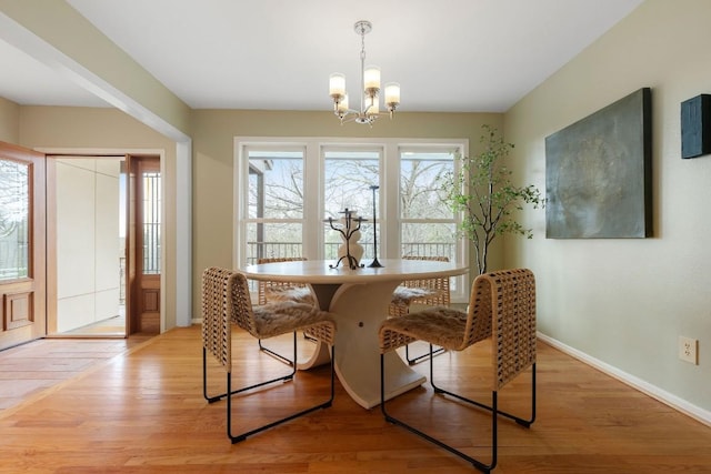 dining space featuring light wood-style floors, a notable chandelier, and baseboards