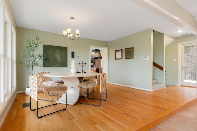 dining space featuring light wood finished floors, stairway, an inviting chandelier, and baseboards