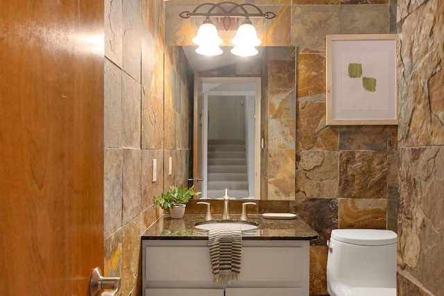 half bath with toilet, tile walls, and vanity