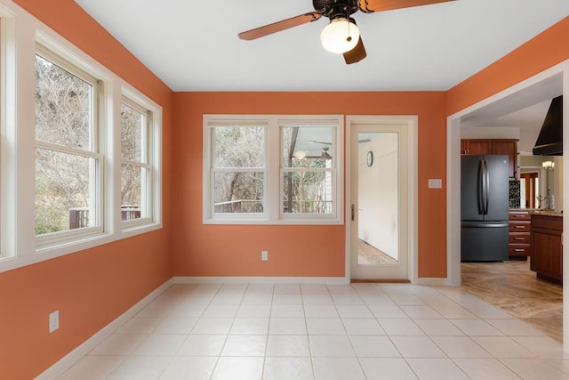 interior space featuring light tile patterned flooring, a ceiling fan, and baseboards