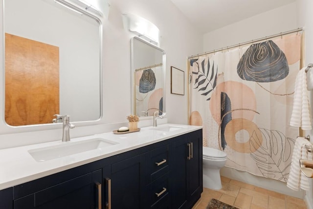 full bathroom featuring double vanity, stone finish floor, toilet, and a sink