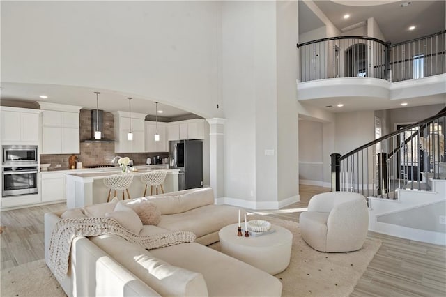 living room featuring light hardwood / wood-style floors, decorative columns, and a high ceiling