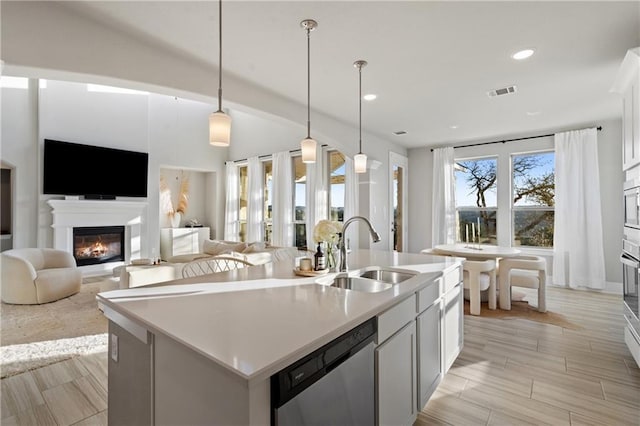 kitchen featuring stainless steel appliances, hanging light fixtures, a center island with sink, and white cabinets