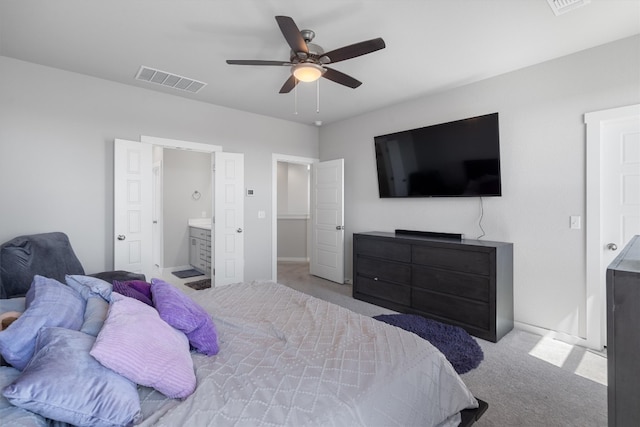 bedroom with ceiling fan, connected bathroom, and light carpet