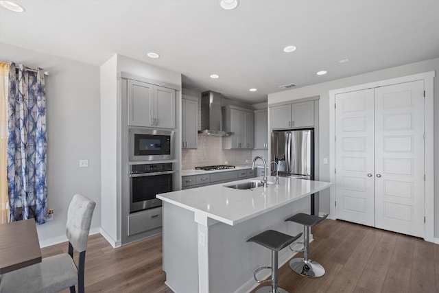 kitchen featuring sink, dark hardwood / wood-style floors, wall chimney exhaust hood, appliances with stainless steel finishes, and gray cabinetry