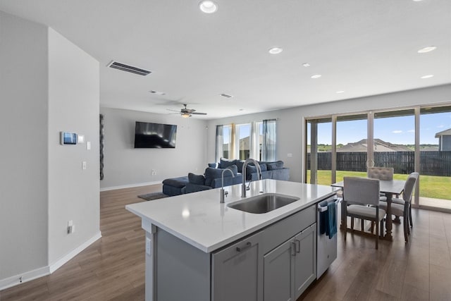 kitchen featuring dishwasher, sink, dark hardwood / wood-style floors, ceiling fan, and a center island with sink