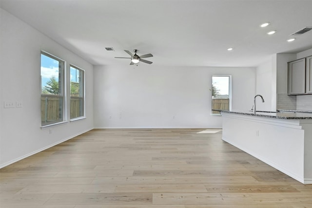 kitchen with stone counters, a healthy amount of sunlight, gray cabinetry, and light wood-type flooring