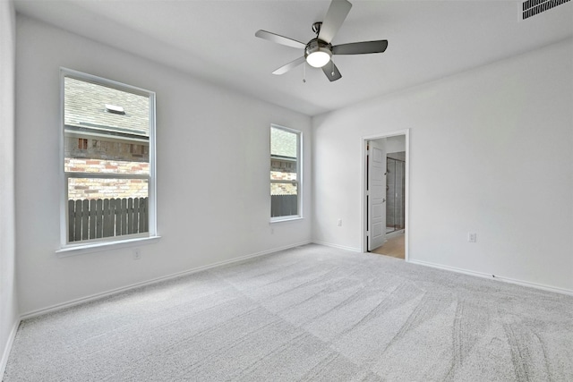 empty room with light carpet, a wealth of natural light, and ceiling fan