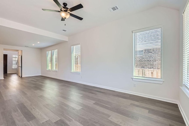 spare room featuring baseboards, visible vents, ceiling fan, and dark wood-type flooring