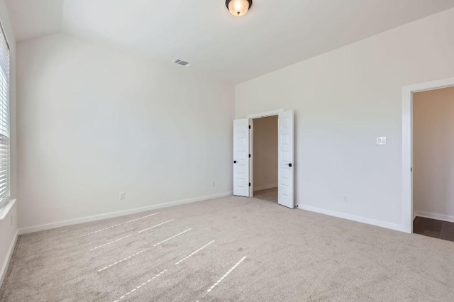 unfurnished bedroom with carpet, visible vents, vaulted ceiling, and baseboards