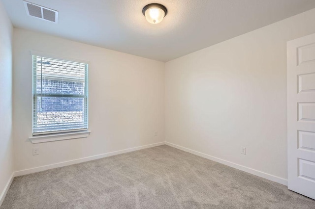 spare room with carpet, visible vents, and baseboards